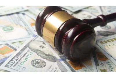 A gavel resting on top a pile of $100 bills, connoting penalties and fines.
