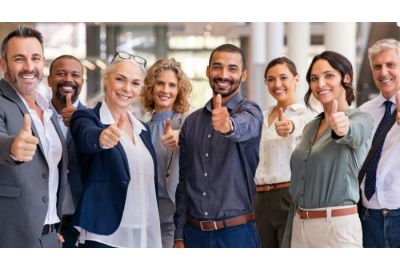 A group of happy, healthy employees raising their thumbs to indicate happiness and positive mental health.